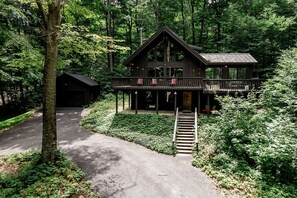 Eine Hütte mit einer Veranda, einer Treppe und einer Auffahrt.