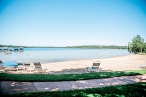 A lakeside beach with lounge chairs and a clear view of the water. - Incredible Cottage with Private Beach and Indoor and Outdoor Swimming Pool in Bellaire, Michigan (Bellaire)