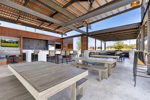 Un espace extérieur aménagé en terrasse, avec plusieurs coins salon, un barbecue et une cheminée en pierre.