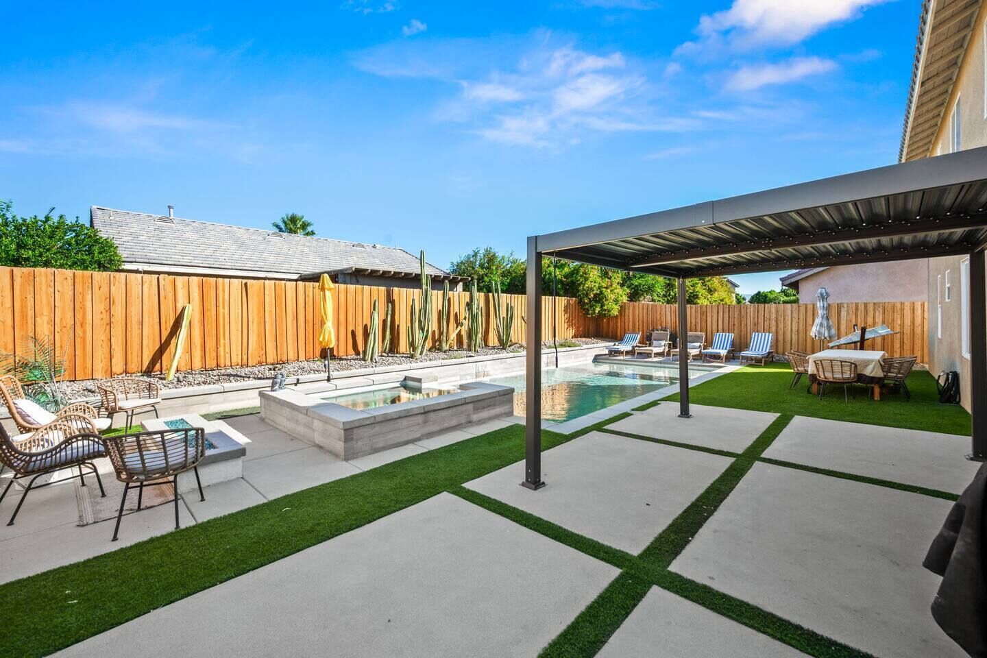 A backyard with a pool, patio furniture, and a covered seating area.