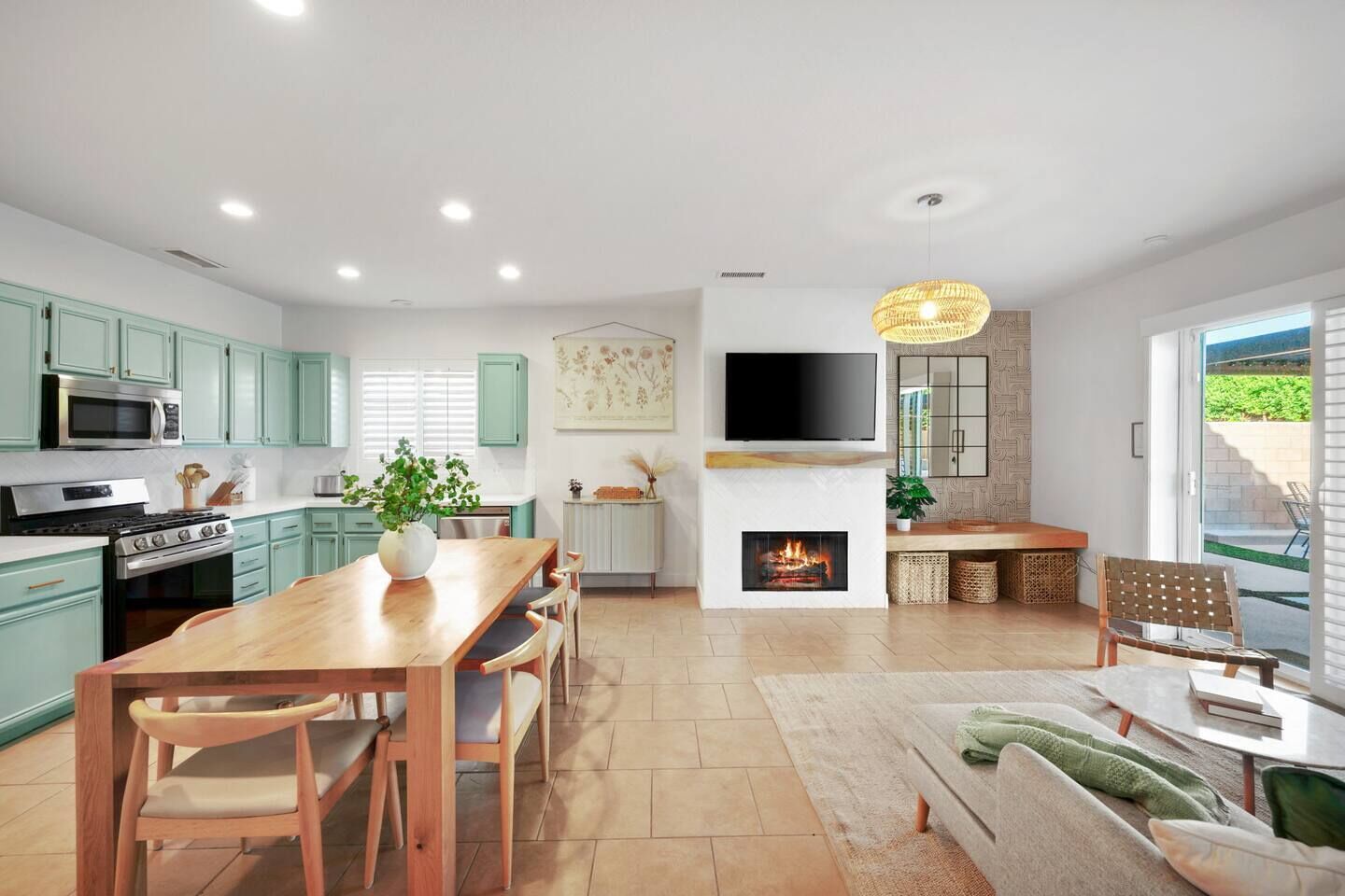 A modern kitchen with a dining area, a fireplace, and a TV mounted above it.