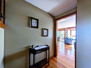 Ein Flur mit Holzboden, einem kleinen Tisch mit einer Vase und Papieren sowie zwei gerahmten Bildern an der Wand.