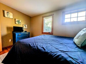 A bedroom with a bed, a dresser, a window with blinds, and wall art. - Charming Waterfront Sea Cottage with Private Beach near Bar Harbor, Hancock Maine (Hancock)