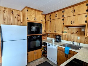 Une cuisine dotée de meubles en bois, d’un réfrigérateur, d’un four, d’un four à micro-ondes, d’un lave-vaisselle et d’un évier.