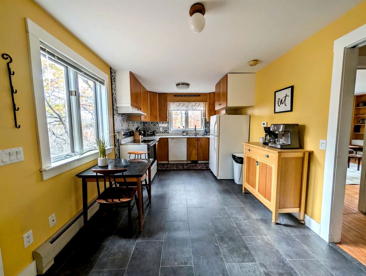 A kitchen with a dining table, cabinets, and a coffee machine.