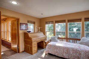Ein Schlafzimmer mit einem Bett, einem Holztisch und einem Fenster mit Jalousien.