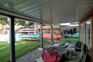 Un espacio al aire libre cubierto con kayaks y una mesa con sillas.