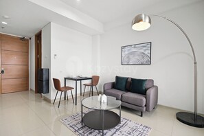 Ein modernes Wohnzimmer mit einem grauen Sofa, einem runden Couchtisch, einer Stehlampe und einem Bild an der Wand.