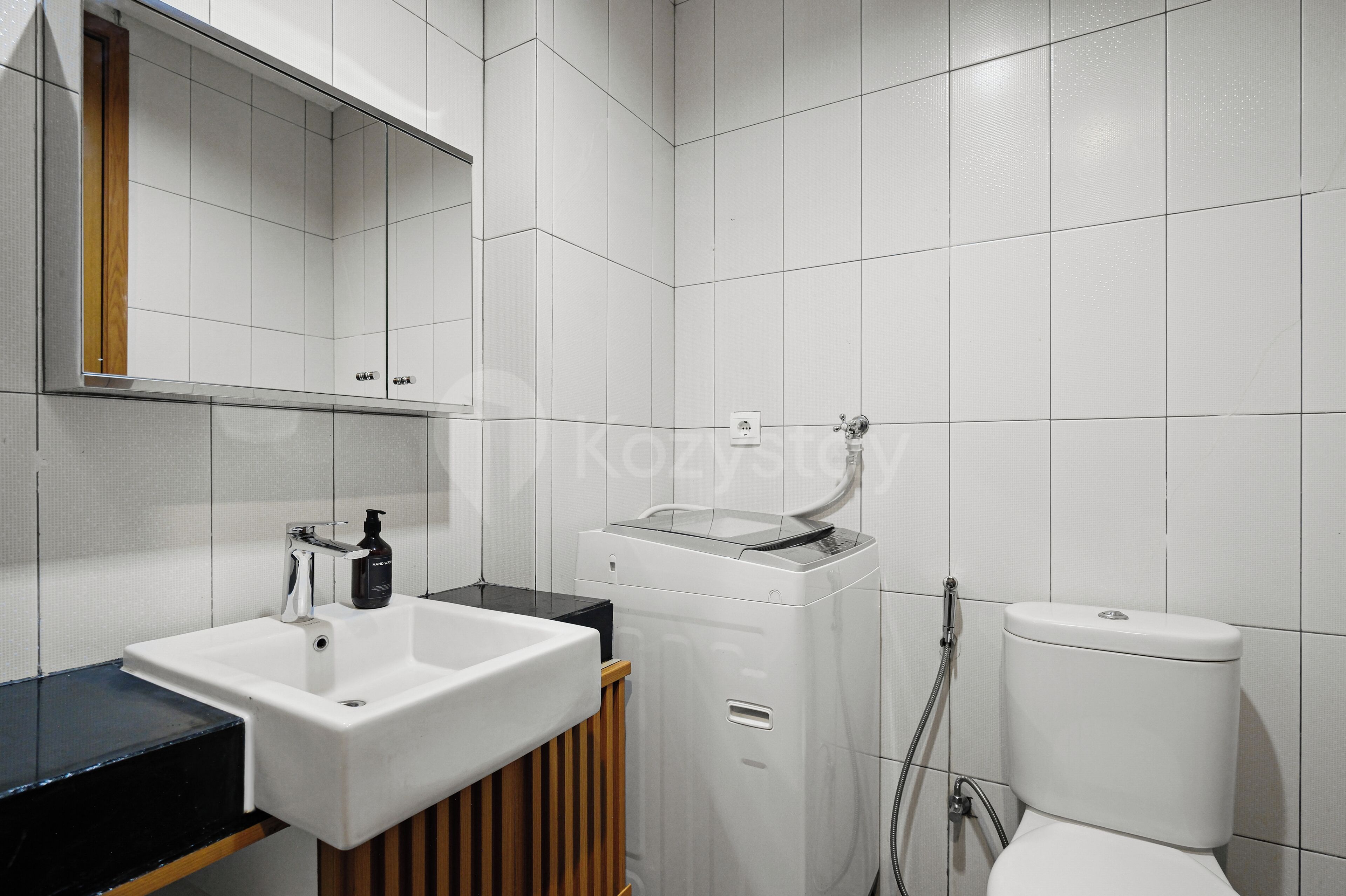 A modern bathroom with a white sink, mirror, and toilet.