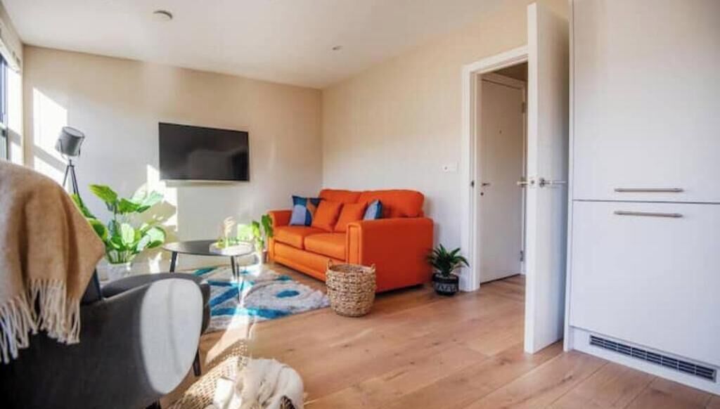 A living room with a sofa, a television, and a door leading to a kitchen.