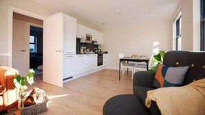 Una sala de estar moderna con un sofá, una mesa de comedor y una cocina al fondo.