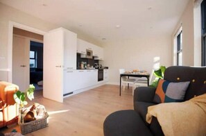 Ein modernes Wohnzimmer mit einer Couch, einem Esstisch und einer Küche im Hintergrund.