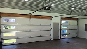 Uma garagem espaçosa com várias portas de garagem, um projetor fixado no teto e piso de concreto.