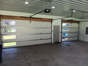 A large garage with multiple garage doors, a projector mounted on the ceiling, and a concrete floor. - The Longview lake house (Coldwater)