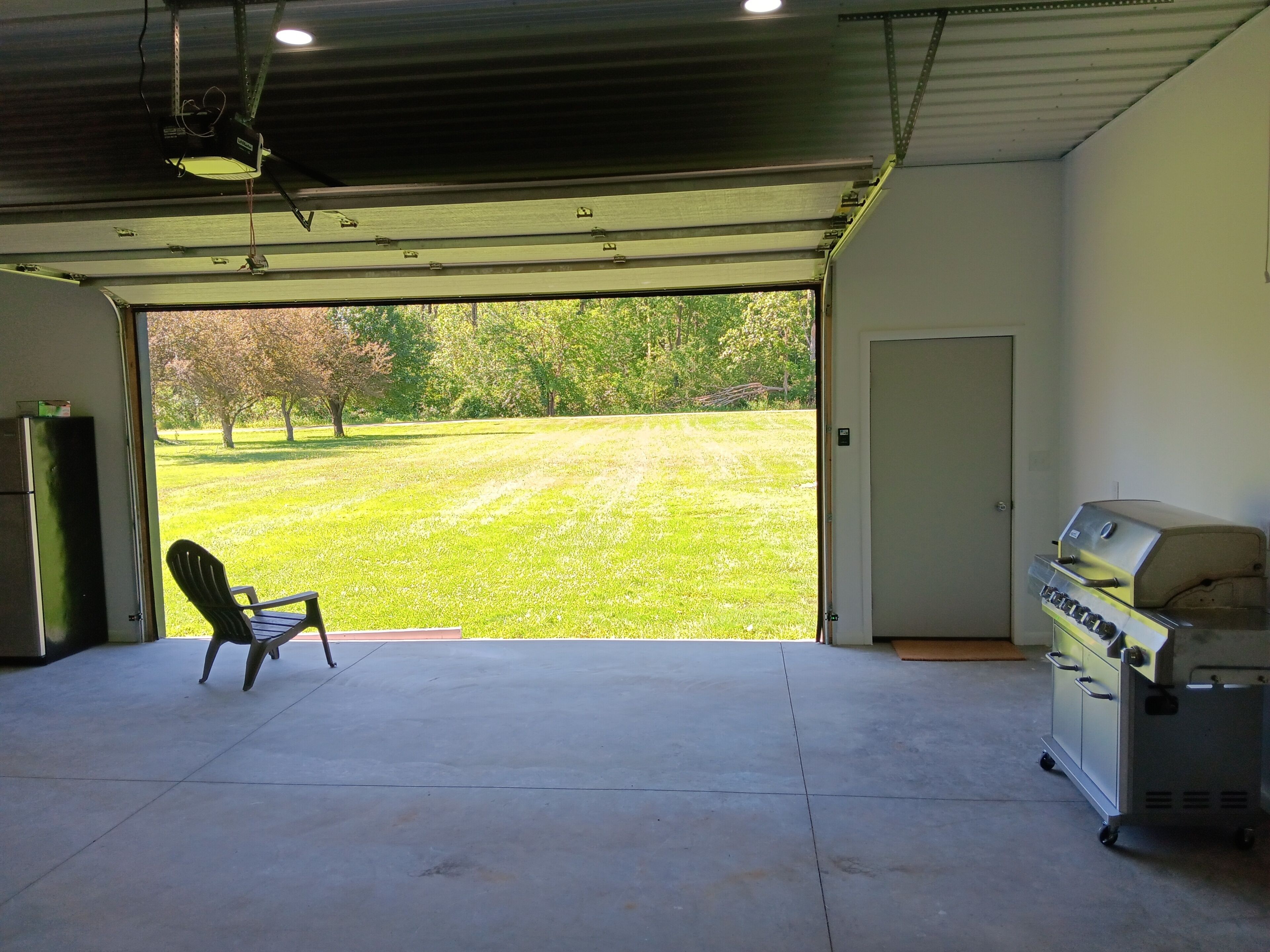 Eine Garage mit Betonboden, Grill und Stuhl.