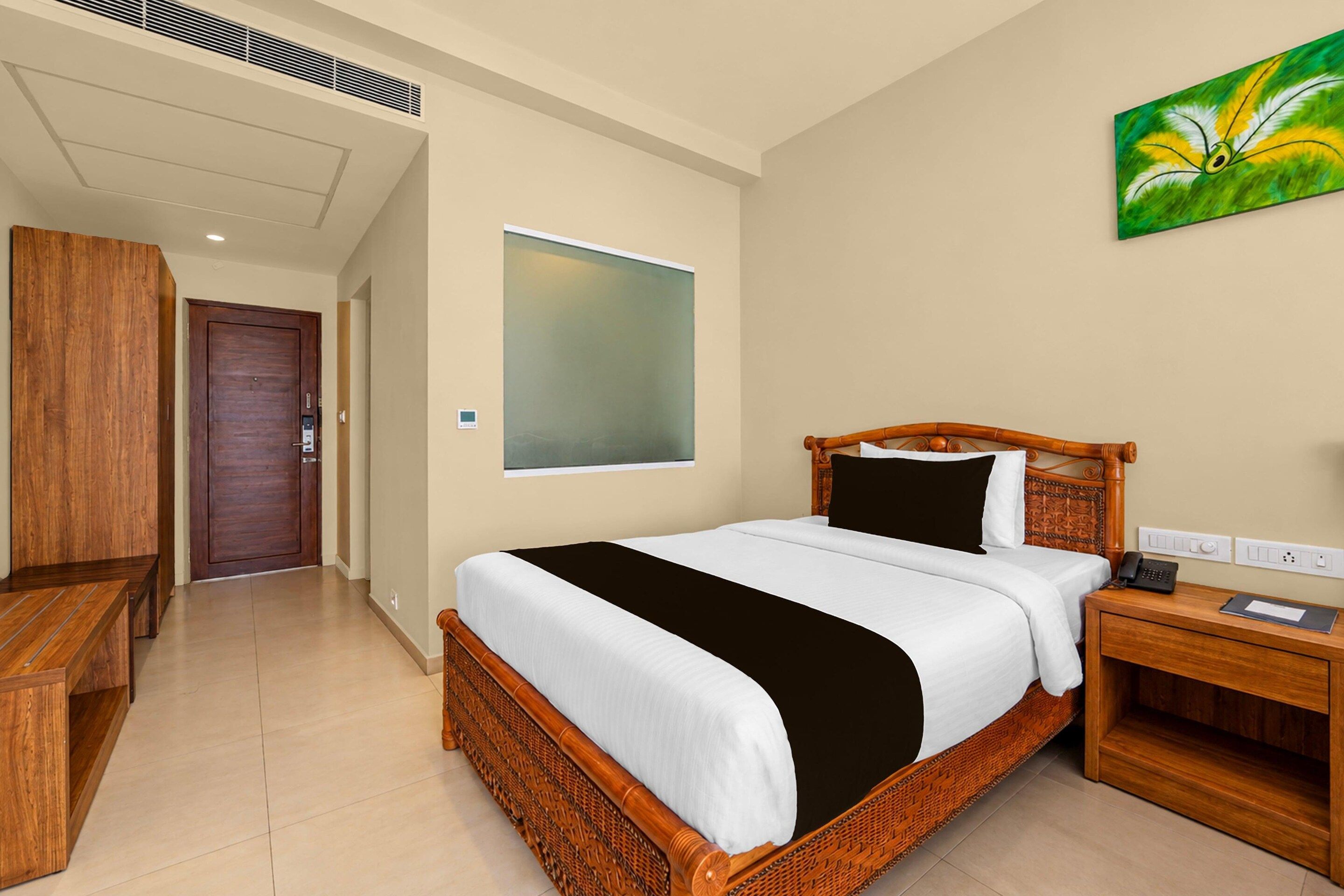 A hotel room with a bed, bedside table, and a painting on the wall.