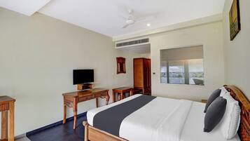 A hotel room with a bed, a television, a desk, and a window.