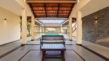 A poolside area with a bench, a stone wall, and a view of a swimming pool.