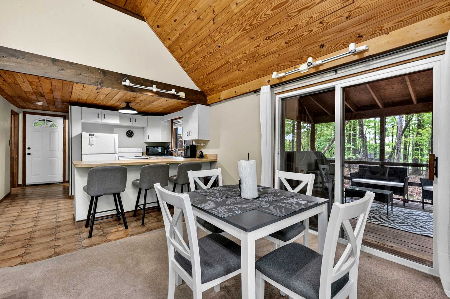A modern kitchen with white cabinets, a central island, and bar stools.
