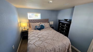 A bedroom with a bed, nightstand, dresser, and a window.