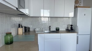 Une cuisine moderne avec des armoires blanches, un four encastré, un évier et une horloge au mur.