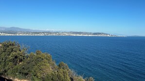 Un paysage urbain côtier offrant une vue dégagée sur la mer et les montagnes lointaines.