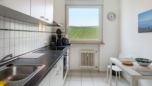 Una cocina moderna con vista a un campo, un lavamanos y un comedor con mesa y sillas.