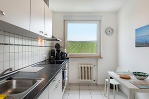 Eine moderne Küche mit Fensterblick auf ein Feld, eine Spüle und ein Essbereich mit Tisch und Stühlen.