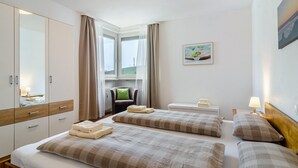 Habitación de hotel con dos camas, una silla, un escritorio y una ventana con cortinas.