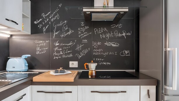 A modern kitchen with a blackboard, a kettle, a coffee pot, and a stainless steel refrigerator. - Aroma Holiday House with Wi-Fi and Air Conditioning (Rome)