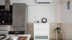 A modern kitchen with a stainless steel refrigerator, white cabinetry, a clock, and a potted plant. - Aroma Holiday House with Wi-Fi and Air Conditioning (Rome)