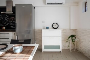 A modern kitchen with a stainless steel refrigerator, white cabinetry, a clock, and a potted plant. - Aroma Holiday House with Wi-Fi and Air Conditioning (Rome)