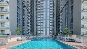 Ein Hochhaus mit Wohneinheiten, einem zentral gelegenen Schwimmbad, zahlreichen Balkonen und moderner Architektur.