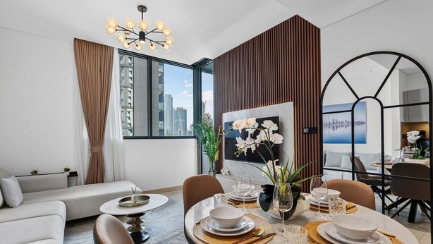 Ein moderner Essbereich mit einem runden Tisch für vier Personen, einer Couch und Blick auf die Stadt.