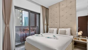 Ein Hotelzimmer mit einem großen Bett, einer Glastür mit Schieberiegel, die auf einen Balkon führt, und einem modernen Kopfteil.