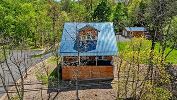 A small house with a blue roof, surrounded by trees and a dirt path.