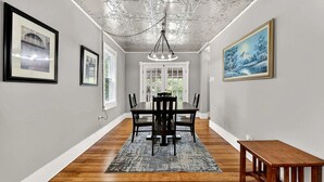A dining area with a wooden table and chairs, a chandelier, framed pictures on the walls, and a view through a glass door. - Secluded Cabin Retreat with Hot Tub in Berkeley Springs, West Virginia (Berkeley Springs)