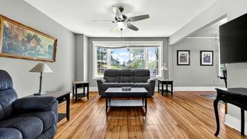 Un salon avec un canapé, une table basse et un ventilateur de plafond.