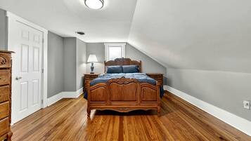 Un dormitorio con una cama de madera, una mesita de noche, un aparador y una lámpara en el techo.