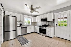 A modern kitchen with white cabinets, stainless steel appliances, a dishwasher, a microwave, and a ceiling fan. - Secluded Cabin Retreat with Hot Tub in Berkeley Springs, West Virginia (Berkeley Springs)