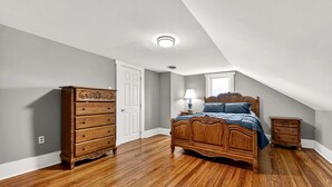 A bedroom with a wooden bed, dresser, and nightstand, a white door, and a window. - Secluded Cabin Retreat with Hot Tub in Berkeley Springs, West Virginia (Berkeley Springs)