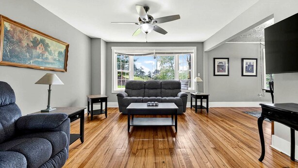 A living room with a sofa, coffee table, and a ceiling fan. - Secluded Cabin Retreat with Hot Tub in Berkeley Springs, West Virginia (Berkeley Springs)