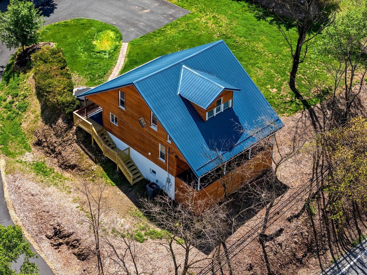 Une maison à deux étages avec un toit bleu, une façade en bois et un petit porche.