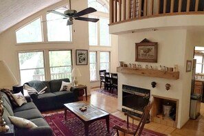 A spacious living room with a fireplace, a ceiling fan, and a dining area.
