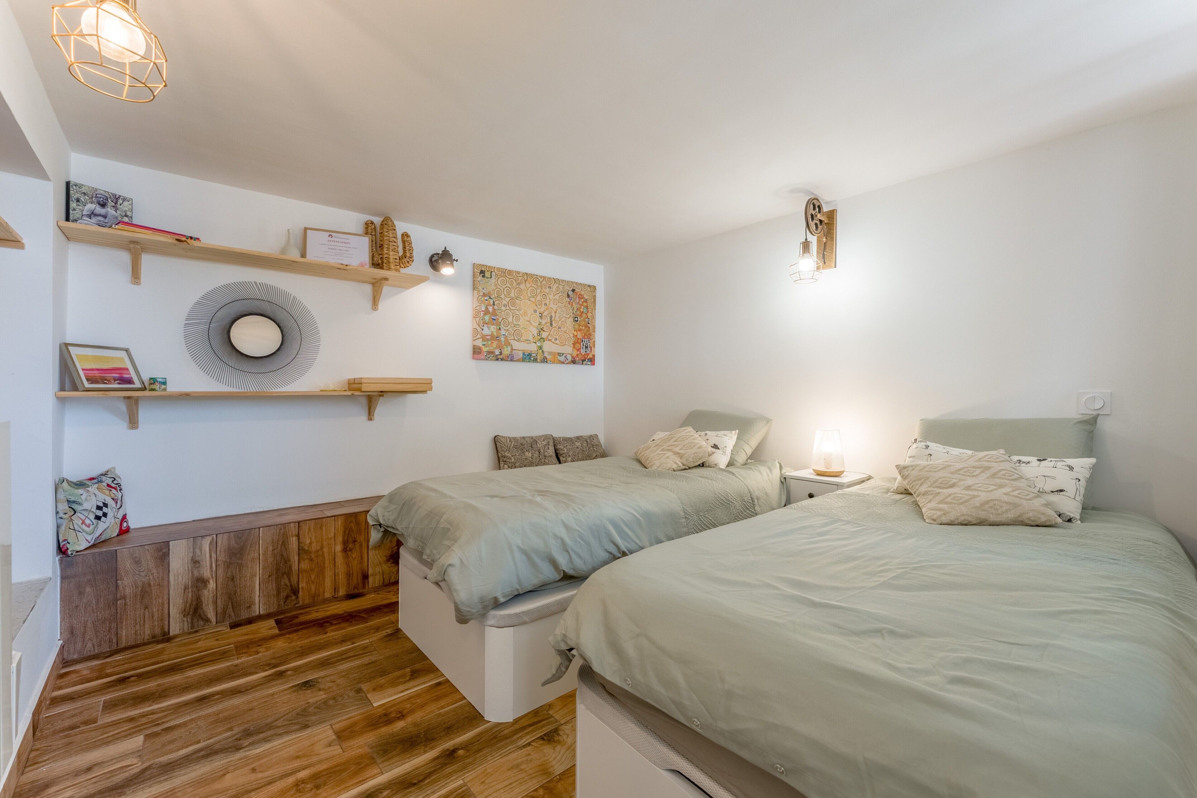 Een slaapkamer met twee bedden, houten vloeren en wandplanken met diverse spullen.