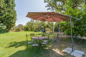 An outdoor patio with a table and chairs, a large umbrella, and a playground in the background.