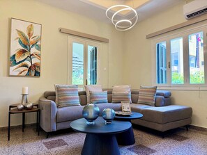 Uma sala de estar moderna com um conjunto de sofás, uma mesa de centro e um quadro na parede.