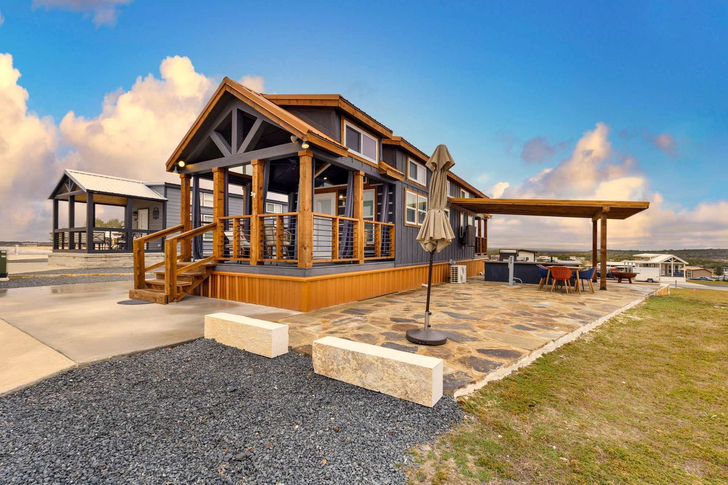 A large, multi-level wooden structure with a covered patio area, outdoor seating, and a view of the surrounding landscape.