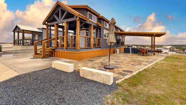 A large, multi-level wooden structure with a covered patio area, outdoor seating, and a view of the surrounding landscape. - Inviting Tiny Home Retreat with Resort-Style Amenities Near Fredericksburg, TX (Fredericksburg)