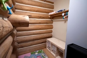 A log cabin-style room with a wooden wall, a small shelf, and a colorful rug.